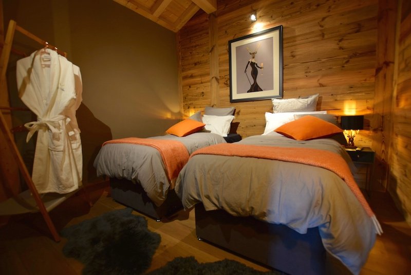 Twin beds with orange throws in Les Gets chalet